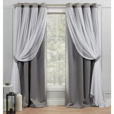 the curtains are open and ready to be hung in front of a window with sheer drapes