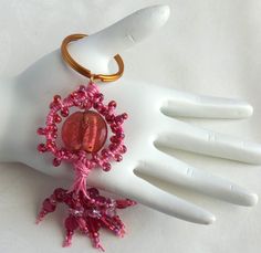 a hand is holding a pink beaded keychain