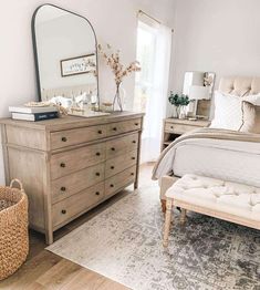 a bedroom with a bed, dresser and mirror on the wall next to a window