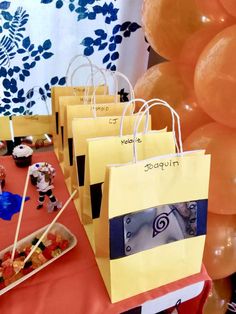 there are many bags on the table with some food in front of it and balloons behind them