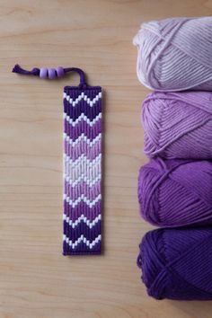 three skeins of yarn next to a crochet bookmark on a table