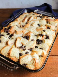 a pan filled with bread and raisins sitting on top of a wooden table