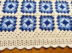 a blue and white crocheted blanket sitting on top of a wooden table