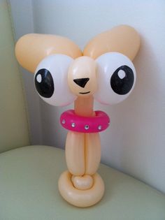 an inflatable balloon shaped like a bear with big eyes and a pink ring around its neck