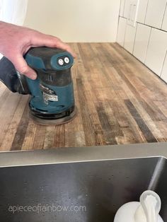 a person using a sander on a wooden counter top