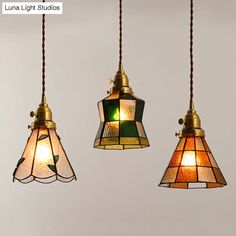 three hanging lights with stained glass shades in various sizes and colors, one light is turned on