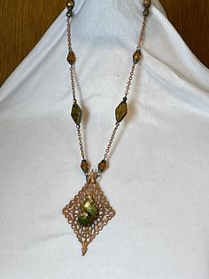 I finally made this beautiful necklace using the amazing vintage Art Deco glass cabochon that I've hoarded since buying it from a great Etsy vendor,  https://www.etsy.com/shop/LilCzechTreasures The glowing copper filigree is topped with the green and gold toned swirly cab with a pinky orange rhinestone. I made the chain using vintage copper chain, glass beads in greens and golds. A copper lobster clasp closure. Chain on each side = 9" Pendant = 3" Total length = 12" OH, PLEASE NOTE THAT THINGS REALLY DO LOOK BETTER IN PERSON, AT LEAST ACCORDING TO ALL THE FEEDBACK I'VE HAD IN THE PAST! Many of my necklaces have chains that can be adjusted for length. Just message me and ask. If it's possible, I'm happy to do so. PLEASE BE SURE TO READ ALL INFORMATION & POLICIES BELOW BEFORE ORDERING I WILL Vintage Bronze Beaded Necklace Gift, Vintage Metal Beaded Necklaces For Gifts, Vintage Metal Beaded Necklace For Gifts, Vintage Cabochon Pendant Necklace, Vintage Wire Wrapped Pendant Necklace, Artisan Gold Necklace From Vintage Collection, Artisan Gold Necklace For Vintage Collection, Vintage Green Copper Jewelry, Green Vintage Copper Jewelry