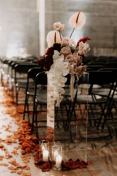 a tall vase filled with flowers and candles on top of a floor covered in petals