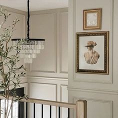 a room with white walls and framed pictures on the wall next to a plant in a vase