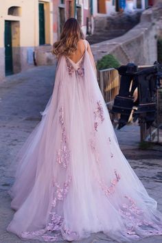 a woman in a pink wedding dress standing on the street with her back to the camera