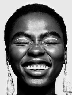 a woman with her eyes closed and wearing earrings on top of her head, smiling at the camera