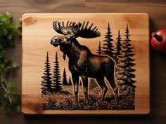 a wooden cutting board with an image of a moose in the woods and pine trees