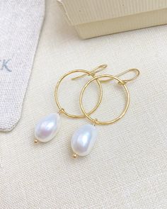 These earrings make it easy to achieve a chic laid-back style. Gold-filled circles are lightly hammered to achieve a faceted texture that reflects the light with every movement. The gold circles are adorned with large oval baroque pearls for a effortless elegance. The gold-filled ear wires are smooth and comfortable for all-day wear. Materials: 14k gold fill, cultured freshwater pearls Earring drop length: 1.5 inches Circle diameter: 3/4 inch Elegant Hammered Drop Hoop Earrings, Elegant Hammered Hoop Earrings, Elegant Hammered Round Hoop Earrings, Elegant Teardrop Hammered Hoop Earrings, Elegant Pearl Jewelry In Circle Shape, Elegant Pearl Circle Jewelry, Elegant Circular Pearl Jewelry, Elegant Circle Pearl Jewelry, Gold Hammered Elegant Pearl Earrings