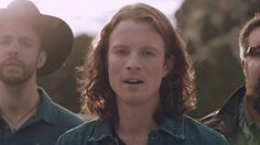 three men with long hair and beards are standing in front of each other wearing hats