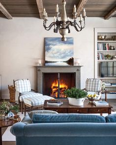 a living room filled with furniture and a fire place under a chandelier hanging from the ceiling