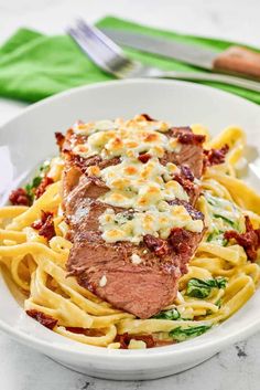 a white bowl filled with pasta and meat covered in sauce on top of a marble table