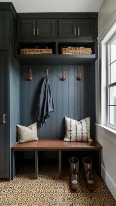 a wooden bench sitting under a window next to a coat rack