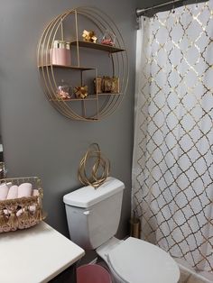 a white toilet sitting next to a bath tub in a bathroom under a gold circular shelf