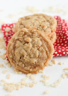 two cookies sitting on top of a red and white napkin next to oatmeal