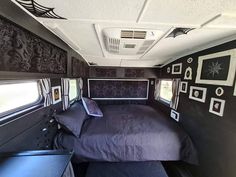 a bed in the back of an rv with pictures on the wall and windows above it