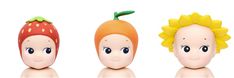 three toy heads with different faces and hair on each head, one in the shape of a carrot