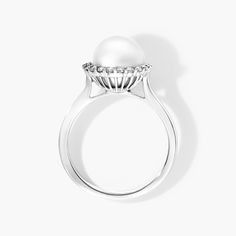 a white pearl and diamond ring on a white background, with the top view showing it's center stone