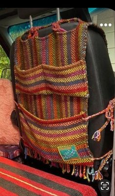 the back seat of a car is filled with colorful blankets and rugs on display