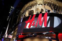 the h & m store is lit up at night with red and black letters on it