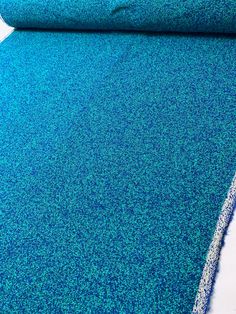 a roll of blue carpet sitting on top of a white floor next to a wall