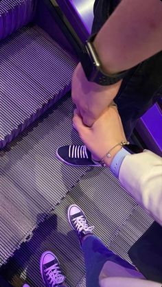 two people standing on an escalator with their feet up and one person wearing sneakers