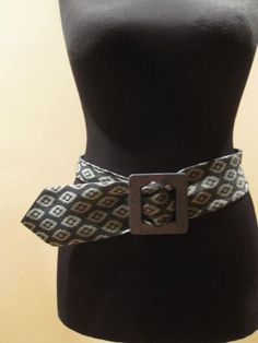 a mannequin wearing a brown and white patterned belt on top of a black dress