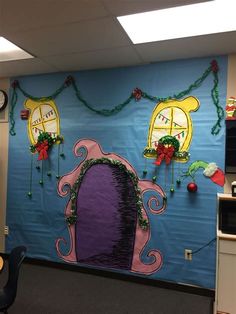 an office cubicle decorated with cartoon characters and christmas decorations on the wall, along with clocks