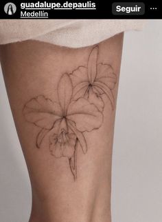 a woman's leg with a flower tattoo on the bottom part of her thigh