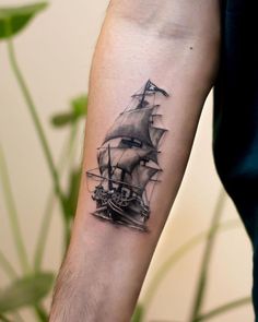 a man's arm with a ship tattoo on it