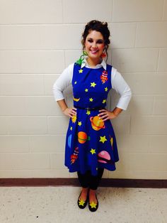 a woman standing in front of a wall wearing a blue dress with planets on it