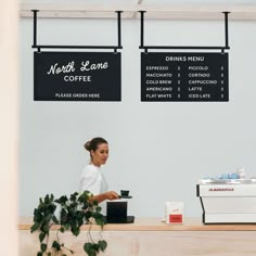 a woman sitting at a counter in front of a coffee shop with menus hanging on the wall