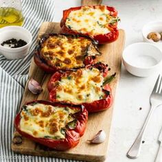 four stuffed bell peppers on a cutting board with garlic and seasoning next to them