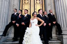 a bride and groom with their bridal party in front of the doors of a building