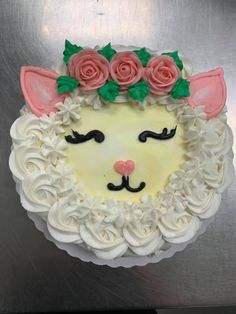 a cake with white frosting and pink roses on it's head is decorated in the shape of a cat