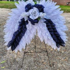 a blue and white flower arrangement on a stand in front of a brick building with grass