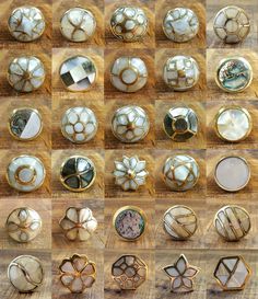 many different types of buttons on a wooden surface with images of them in gold and white