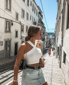 a woman is walking down the street with her hand on her hip and looking off into the distance