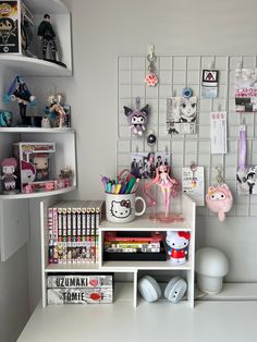 a white desk topped with lots of books and toys next to a shelf filled with anime figurines