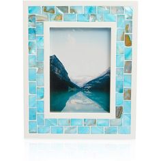 a blue mosaic frame with mountains in the background and water reflecting on the glass surface