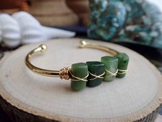 ✦ DETAILS ✦✧ Genuine Natural Nephrite Jade Crystals✧ Stones measure approx. 11x8mm but each stone is different ✧ Gold plated bangle cuff.✧Also available in amazonite, apatite, black tourmaline, and kyanite✧Usually ships same day or next day and comes ready for gifting in a cute boho gift box.For thousands of years, the stone has been revered in China and other countries throughout the world. The Chinese believed that since jade objects lasted so long, they were linked to immortality. They believ Spiritual Style Jade Bangle Jewelry, Spiritual Green Bangle Cuff Bracelet, Adjustable Green Cuff Bracelet With Natural Stones, Green Gemstone Cuff Bracelet For Gift, Green Bangle With Natural Stones For Gift, Green Gemstone Bangle Cuff Bracelet, Jade Gemstone Bangle As Gift, Spiritual Jade Bangle For Gift, Green Hand Wrapped Bangle Jewelry