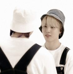 two young men standing next to each other in front of a person wearing a hat