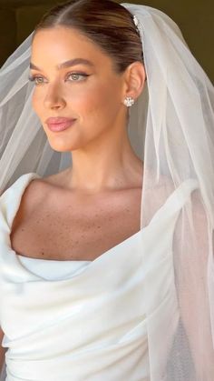 a woman wearing a wedding veil and posing for the camera