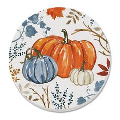 a white plate with blue and orange pumpkins on the front, surrounded by autumn leaves