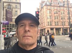 a man wearing a hat standing in front of a traffic light on a city street