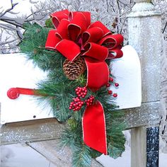 a mailbox decorated with red ribbon and pine cones